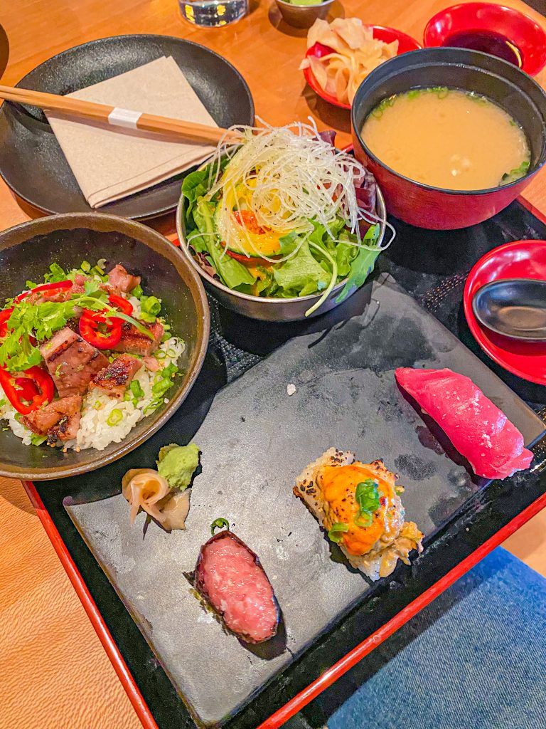 Foto de uma bandeja com diversos sushis e saladas 