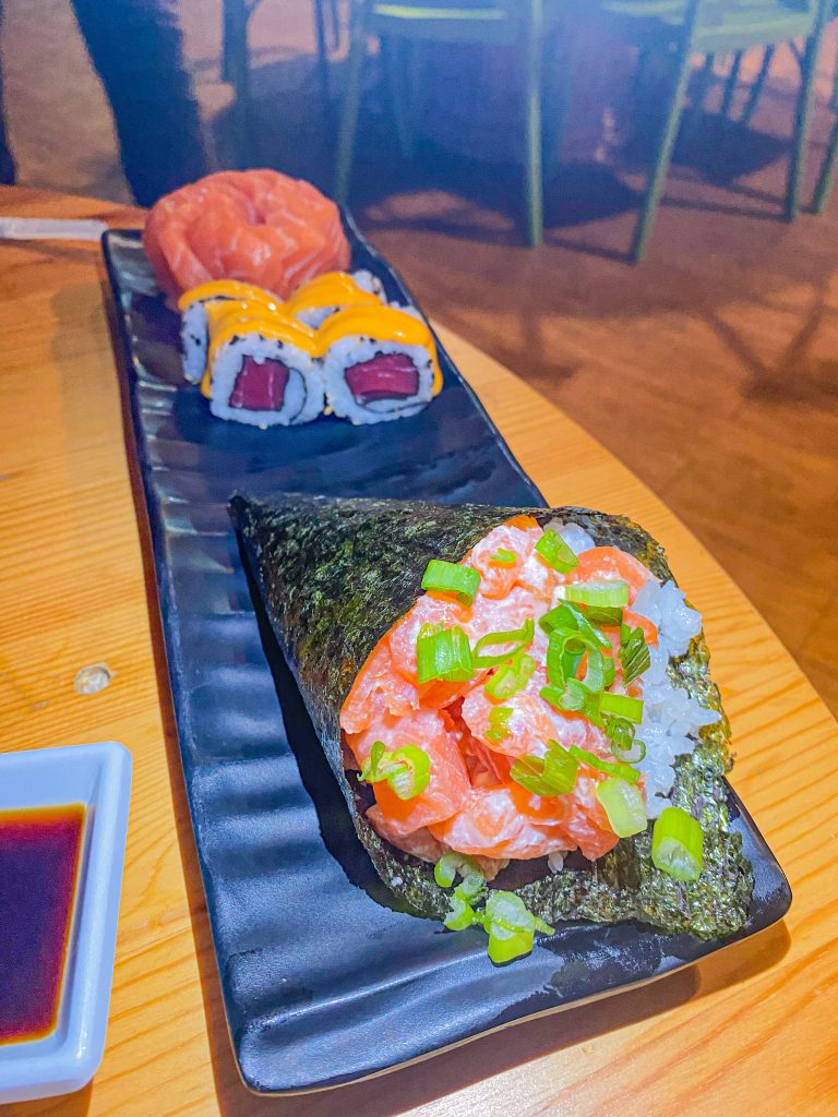 Foto de um temaki de salmão com cebolinha e sushi de atum