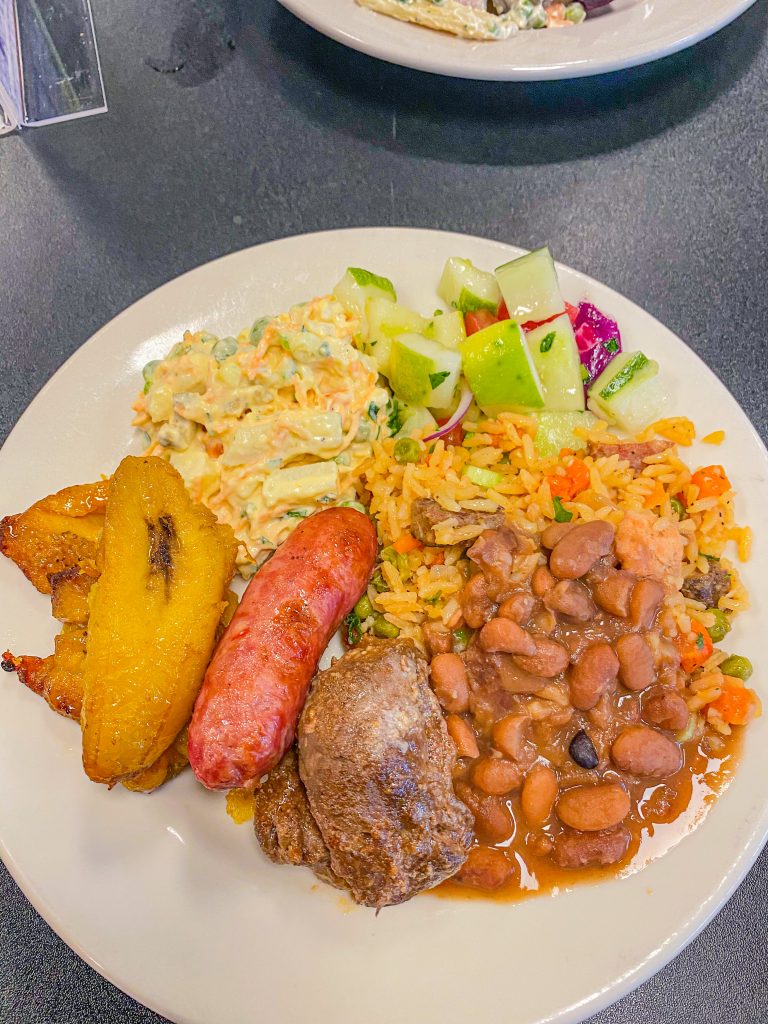 Foto de um prato de arroz, feijão, salada, banana da terra, linguiça e bife