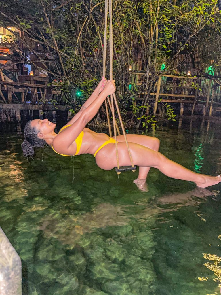 Foto da Camilli sentada num balanço com biquíni amarelo num Cenote em um restaurante lugares instagramaveis de Tulum