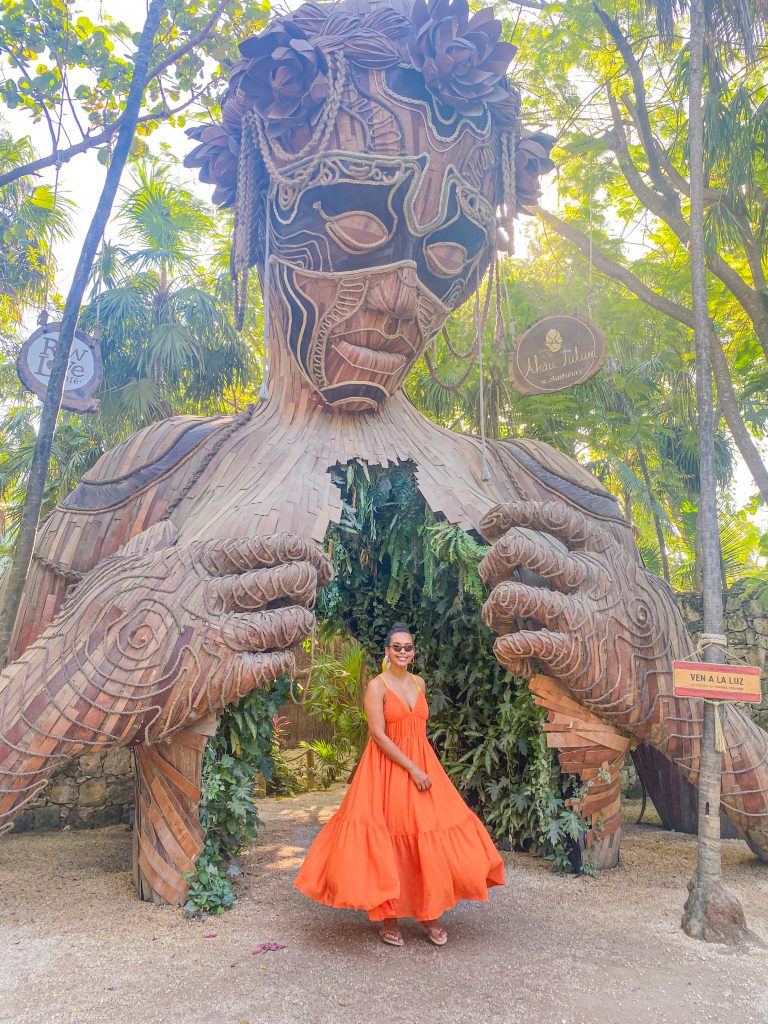 Foto da Camilli em vestido laranja em frente ao hotel Ahau lugares instagramaveis de Tulum