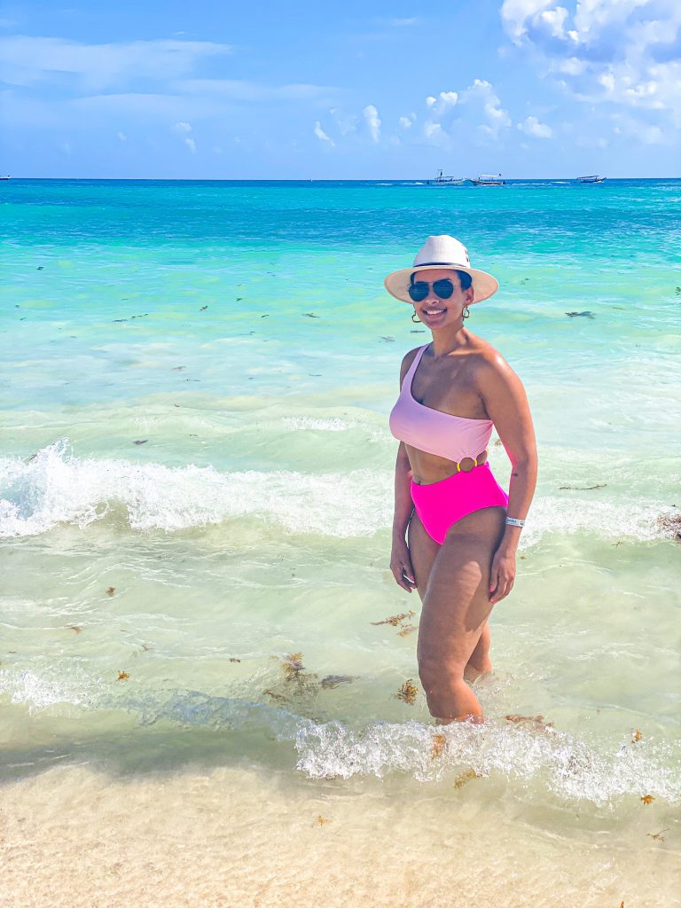 Foto da Camilli, com maio rosa, óculos de sol e chapéu branco no mar em Playa del Carmen